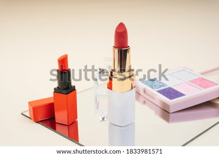 Cosmetic collection - Lipstick and palette in pastel tone on mirror plate over white background.