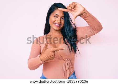Beautiful latin young woman with long hair wearing casual clothes smiling making frame with hands and fingers with happy face. creativity and photography concept. 