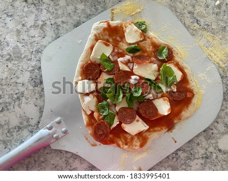 Homemade pizza on a pizza peel in a kitchen at a home.