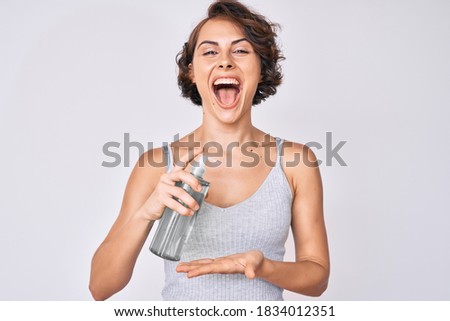 Young hispanic woman using hand sanitizer gel smiling and laughing hard out loud because funny crazy joke. 