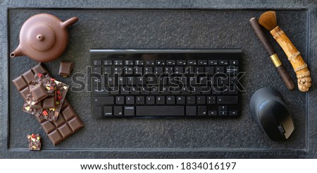 Laptop, sweets, chocolate, teapot on a black stone table. Snacking while working concept
