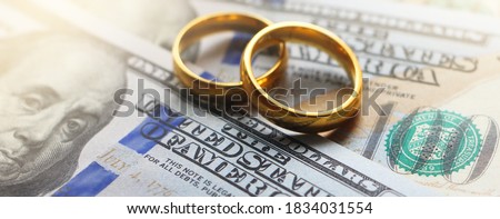 Wedding rings on the background of 100 dollars bills. Marriage conctract or prenuptial agreement concept Royalty-Free Stock Photo #1834031554