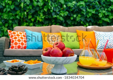 Lemonade red apples with colorful pillows and snacks on garden furniture outdoors Royalty-Free Stock Photo #1834034704