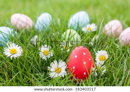 Red Easter egg in a nest of grass and spring flowers