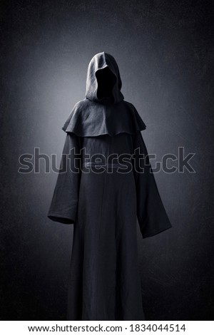 Scary figure in hooded cloak Royalty-Free Stock Photo #1834044514