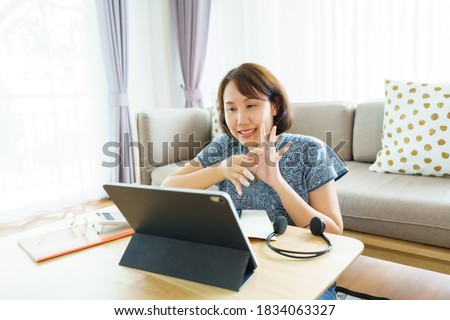 Asian woman aged 30-35 years using tablet, watching lesson Sign language online course communicate by conference video call from home, e-learning education concept