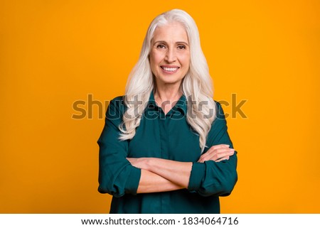 Photo of pretty cheerful white haired grandma lady holding hands crossed responsible chief company ceo founder wear green shirt isolated bright yellow color background