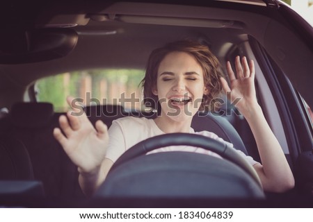 Photo of positive cheerful girl funky driver rider enjoy drive ride car under pop star hits playlist music try dance raise hands in city center Royalty-Free Stock Photo #1834064839