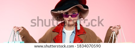 panoramic shot of woman in sunglasses and hats with sale tag holding shopping bags isolated on pink Royalty-Free Stock Photo #1834070590
