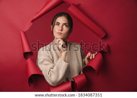 Caucasian young brunette happy woman thinking and looking upward at copyspace isolated through red background