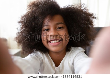 African American cute little girl taking selfie and having fun at home. people, kid and education concept