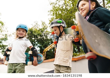 Happy cheerful kids with skateboards at the ramp, holding skateboards