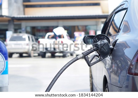 Fueling the car at the gas station with a black nozzle.
