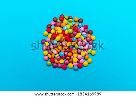 Multi-colored round candies lie on a sparkling blue background. Festive mood. Top view