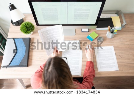 Top view of the workspace and office of a female translator working on a document and checking some references Royalty-Free Stock Photo #1834174834