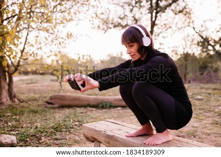 Woman in sport clothes on a wooden bench taking a selfie