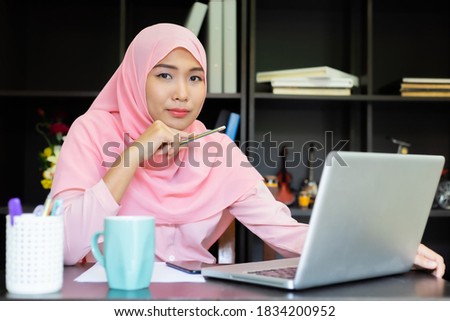 Asian woman muslim shirt pink. Business women hand with paper writing at graph, Using Computer Notebook laptop and smartphone, Felling happy Marketing business for success Concept.