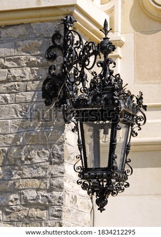 an old lantern in black metal with a lot of decoration belonging to the castle building                      