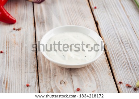 Side view on white sour cream sauce on the light wooden background