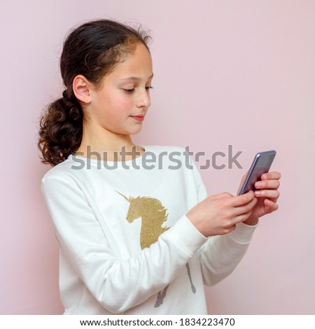 Young black hair girl with cellphone on blushing pink background.