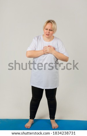beautiful young plump woman in a white t-shirt with a pain in the heart