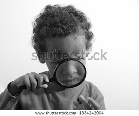 boy looking through a magnifying glass at school on white background stock photo