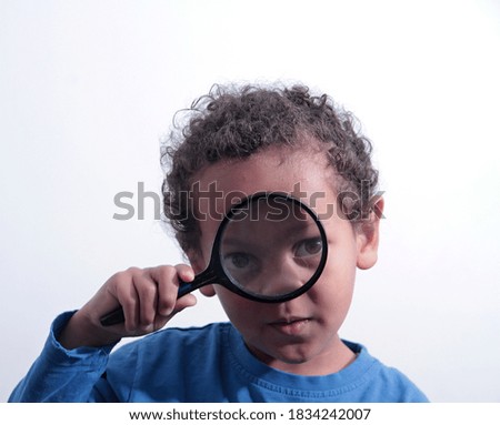 boy looking through a magnifying glass at school on white background stock photo