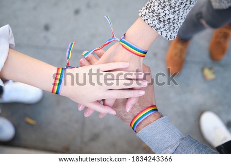 Hands of a group of three people with LGBT flag bracelets. LGBT pride celebration. Royalty-Free Stock Photo #1834243366