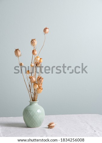 bouquet of dried flowers poppies in a green vase on a linen tablecloth on light green  background. Front view and copy space