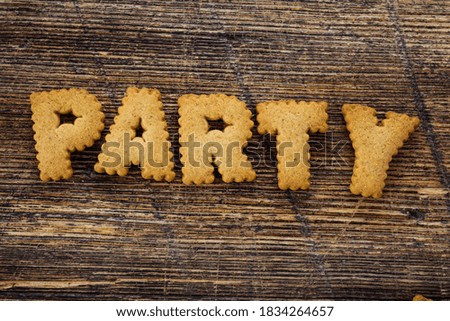 Top view of many letter shaped cookies on rustic wooden background, forming the word PARTY.