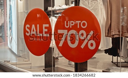 White text on the red sticker on the glass of window in the store with the inscription sale up to 70% off