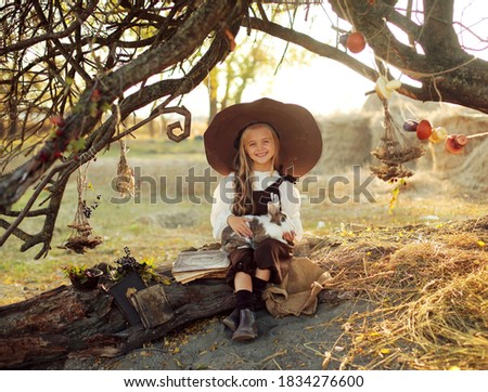 Halloween. cheerful witch with a magic wand and a book conjures and laughs. little girl in a witch costume