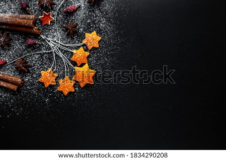 On a black background,a layout of stars of orange peel, anise and rosehip berries.The concept of new year and Christmas.