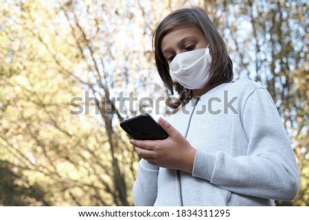 Young teenager with protective mask chatting on mobile phone, selective focus