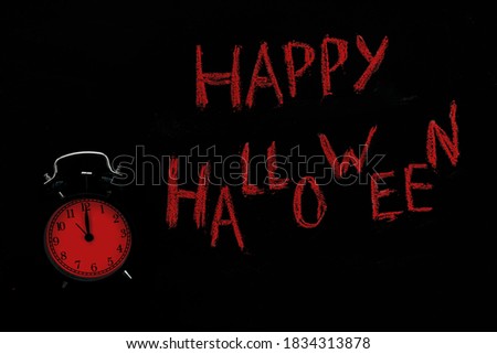 Halloween decoration card with inscription Happy Halloween and clocks in red color for celebration design. Black background. Flat lay.