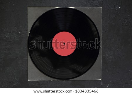 Aged black paper cover and vinyl LP record isolated on black background