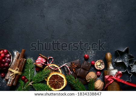 Christmas baking background with ingredients for making cake or biscuit on a black slate, stone or concrete table. Top view with copy space.