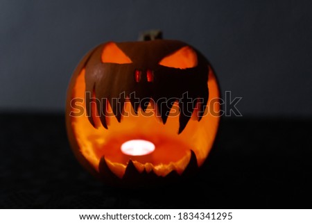 Glowing and terrified halloween pumpkin with a candle inside. Smiling Jack O' Lantern.