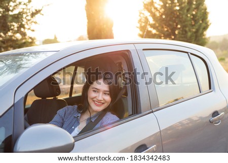 Happy woman driving a car and smiling. Cute young success happy woman is driving a car. Portrait of happy female driver steering car with safety belt