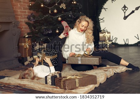 Family with cristmas gifts. Little girl near christmas tree. Beautiful mother in a white sweater.