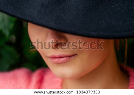 girl hiding her face behind a black hat outdoors