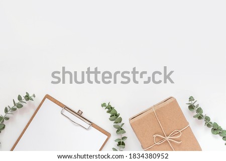 Craft paper holder and gift box with eucalyptus branches on white background minimalistic flat lay composition