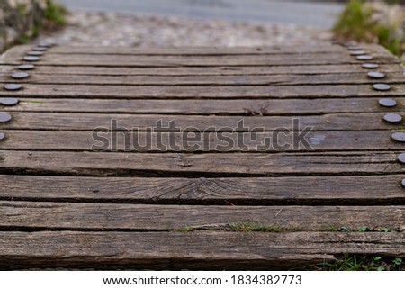 Old wooden boards of a bridge with round iron rivets.
