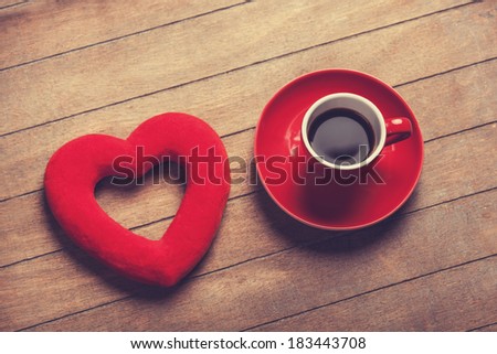 Cup of coffee and shape heart on a wooden table.