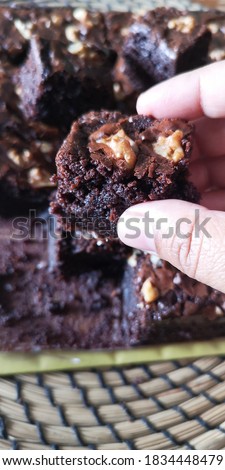 holding a piece of brownies with a walnut on the top. picture blurred dew to selected focus.