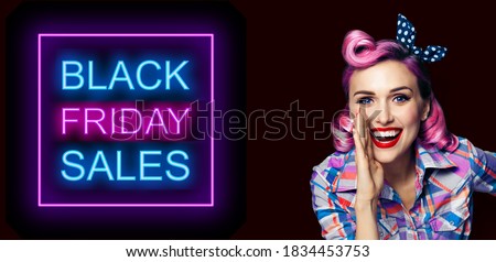 Beautiful happy excited woman holding hand near open mouth. Girl dressed in pin up. Blond model at retro fashion vintage advertising concept, over dark background. Black Friday sales neon light sign. 