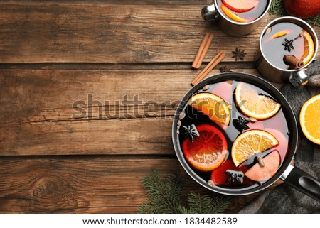 Delicious mulled wine and ingredients on wooden table, flat lay. Space for text