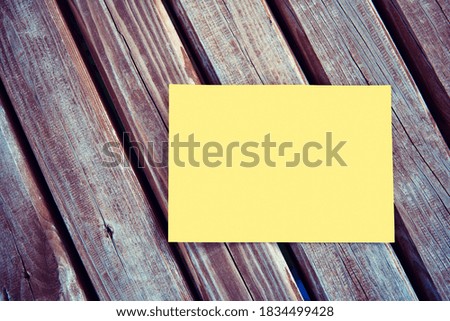 Blank empty yellow paper mock up on a wooden table in outdoor.