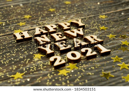 Happy New year 2021 celebration. Wooden text on wooden background with scattered golden confetti