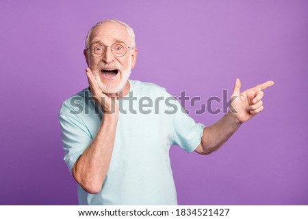 Photo portrait of screaming man touching face with one hand pointing finger to side isolated on vivid purple colored background